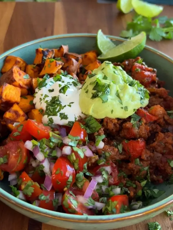 Assembling a loaded potato taco bowl with toppings