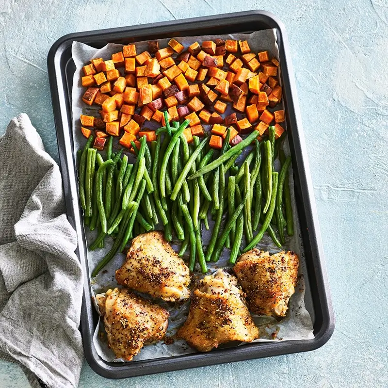 A heavy-gauge rimmed half-sheet pan placed on a kitchen counter ready for sheet pan cooking