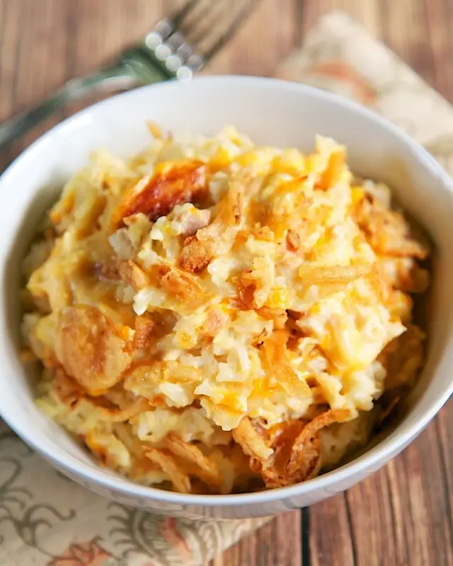 Raw chicken thighs placed over rice and broth mixture in a casserole dish before baking