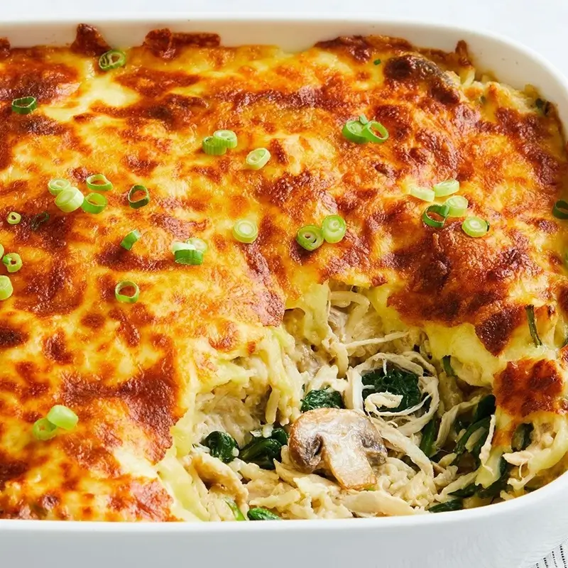 Shredded cheese melting over golden chicken in a French Onion Rice Bake fresh out of the oven