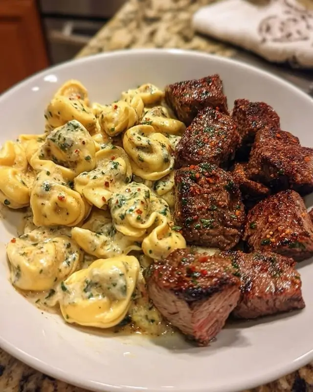 Garlic butter sauce simmering in a skillet with cheese tortellini and steak bites