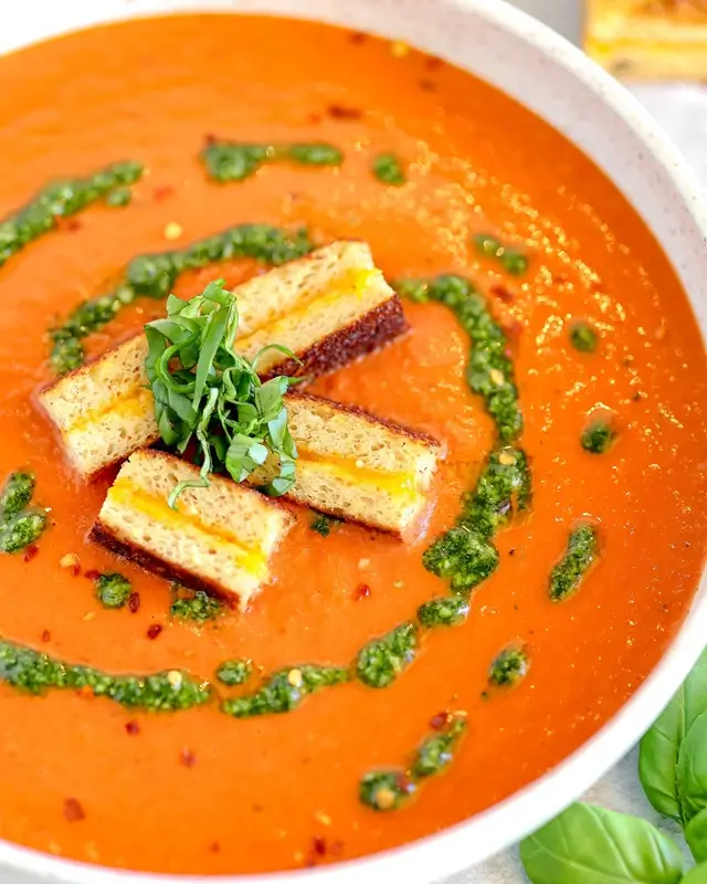 A golden grilled cheese sandwich beside a bowl of warm tomato soup, a classic cheap dinner for college students