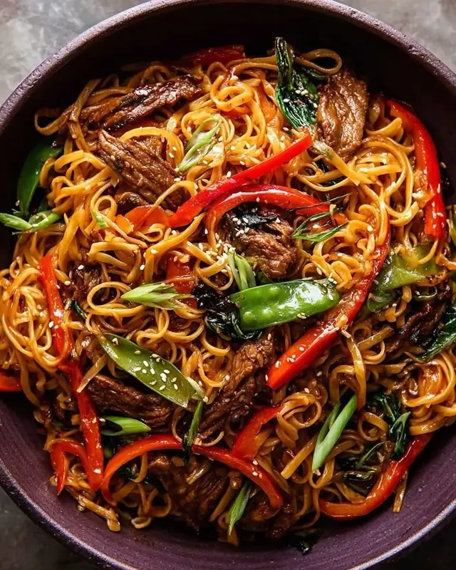 Final serving of high protein sticky garlic chicken  noodles in a white bowl with sesame seeds and  fresh scallions on top