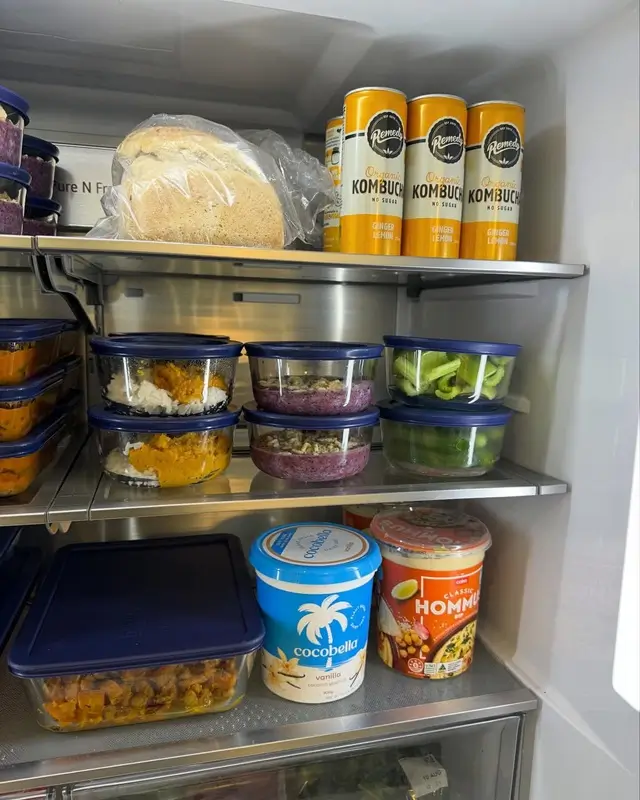  Organized refrigerator shelf with labeled meal  prep containers sorted by day, showing proper  dinner storage for the week