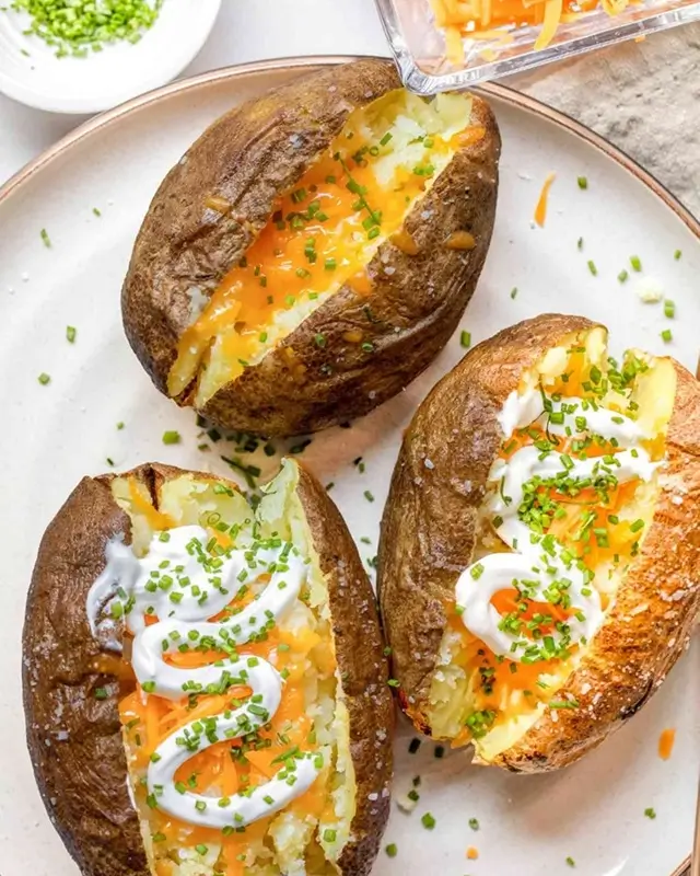 A loaded microwave baked potato topped with butter cheese and canned chili, a quick and cheap student dinner