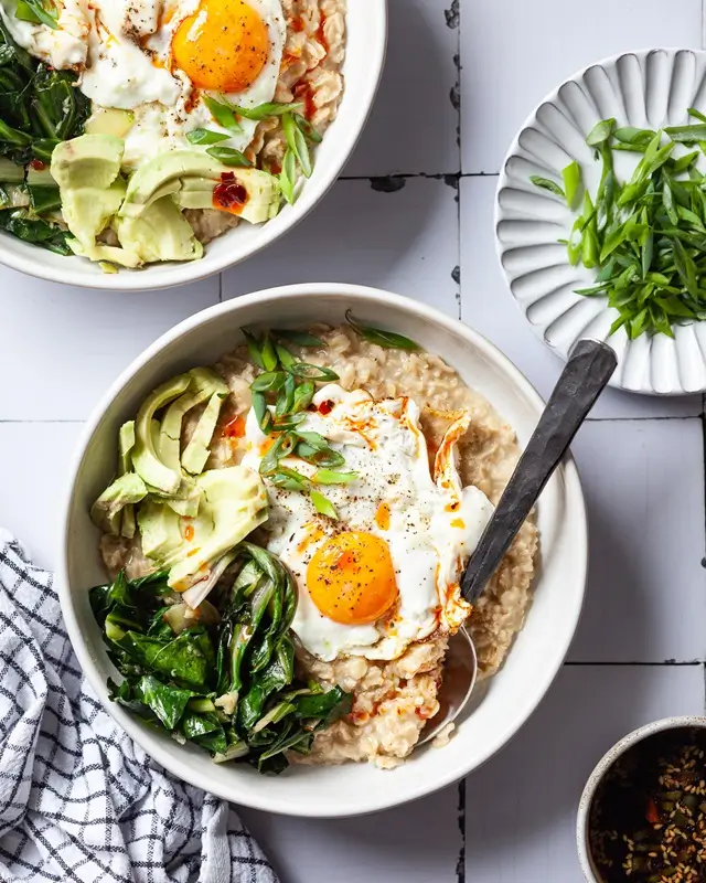 A savory oatmeal bowl topped with a poached egg soy sauce and green onions, an affordable and filling college dinner